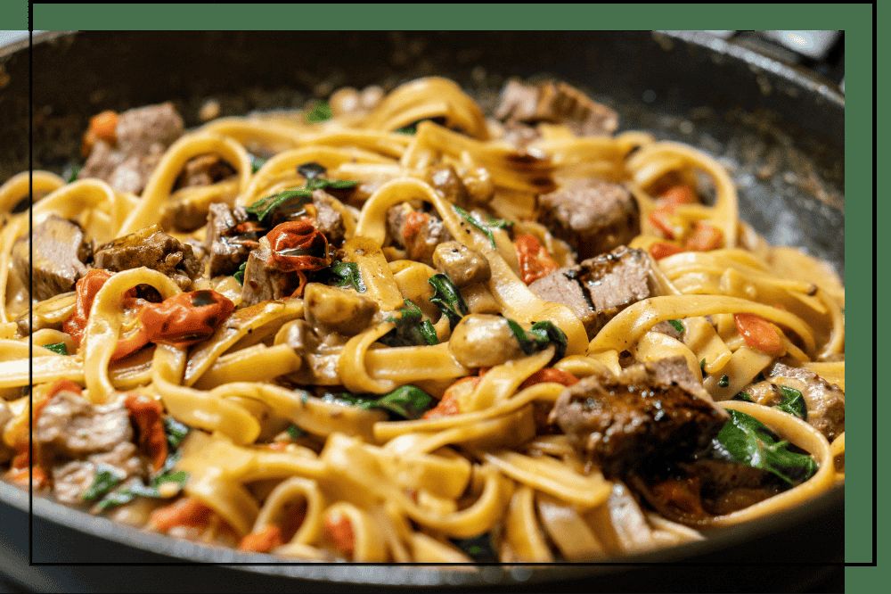 Fettuccine with seared beef, tomatoes, and spinach in a skillet, noodle catering in DFW